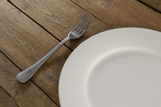 木桌上白色盘子和叉子的上方