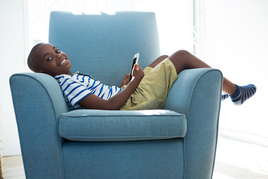 在沙发上玩手机的小男孩