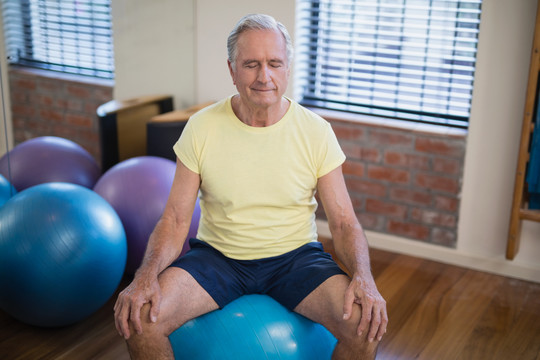 理疗师对健身球上的老人做按摩