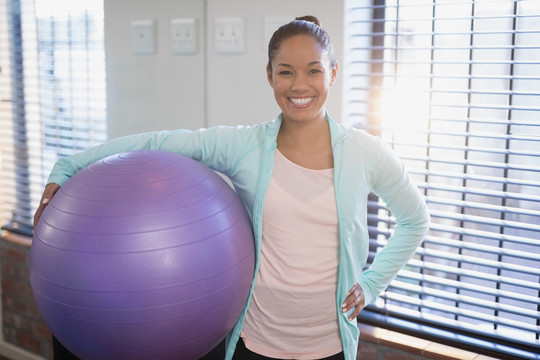 年轻女性理疗师举着紫色健身球
