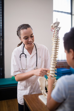 女性治疗师指着人造脊柱解释