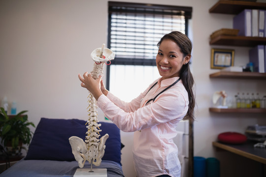 女性治疗师在床上检查人造脊柱