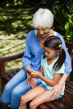 坐在长椅上微笑的孙女和祖母