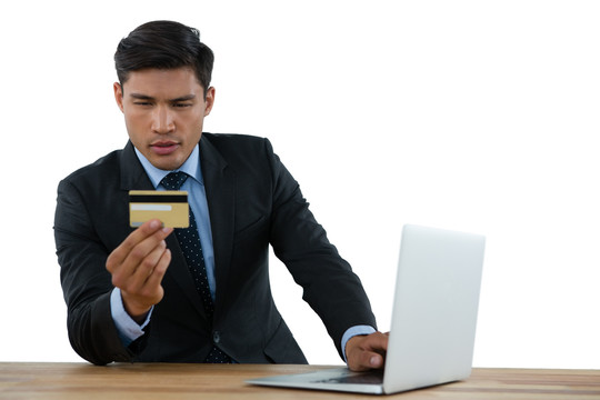 商人在使用电脑时持有信用卡