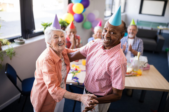 戴着派对帽跳舞的老年夫妇
