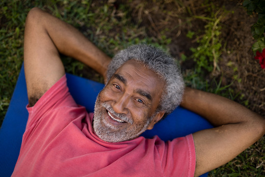 老年男性躺在运动垫上休息时画像