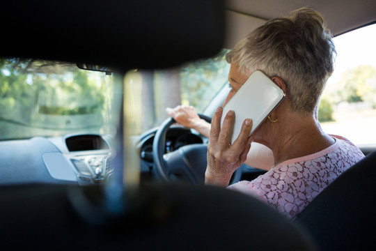 在开车时用手机说话的老年妇女