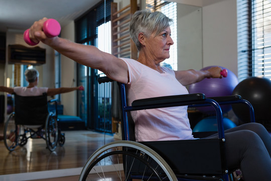 坐轮椅的老年妇女用哑铃做运动