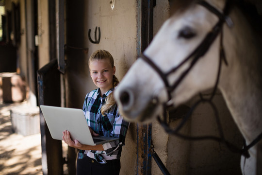 少女在马厩里用笔记本电脑