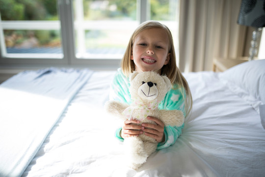 卧室里的抱着泰迪熊的小女孩