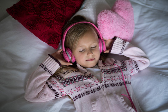 躺在床上用耳机听音乐的女孩