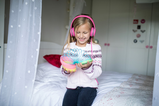 小女孩用耳机玩弹簧玩具