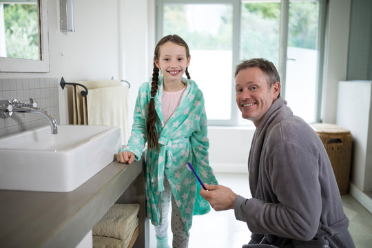 微笑的父亲和女儿在浴室刷牙