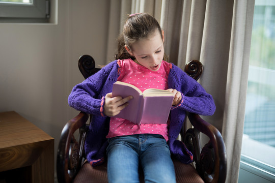 女孩在客厅的椅子上看书