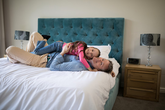 微笑的父亲和女儿躺在卧室的床上