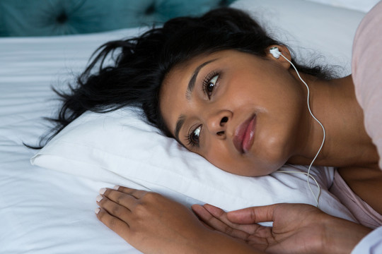体贴的女人在床上听音乐