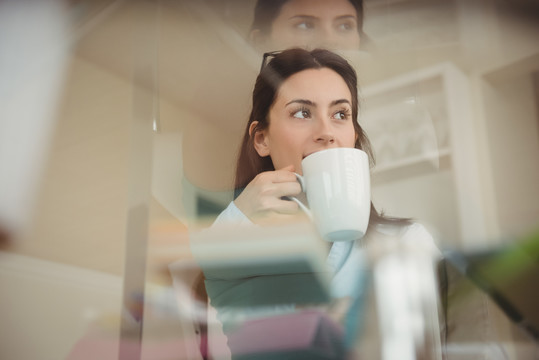 女人坐在家里的玻璃桌旁喝咖啡