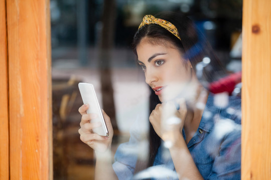 坐在咖啡店时拿着智能手机的女人