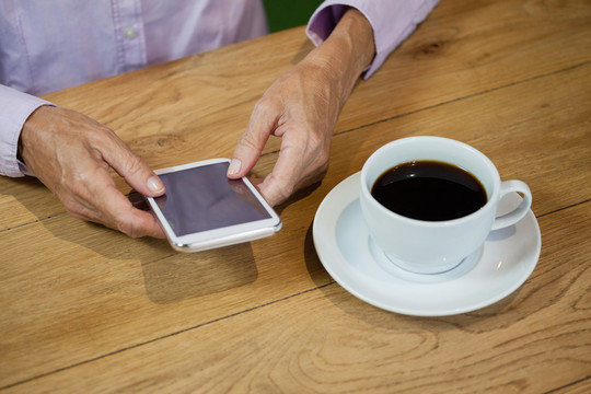 咖啡厅里使用智能手机的老年女性