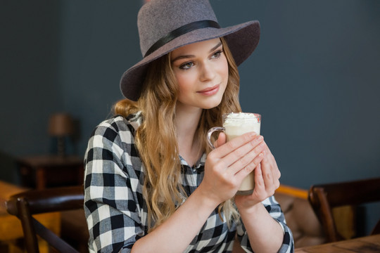 年轻女子边看边在咖啡厅拿冷咖啡