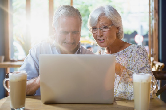 老年夫妇喝咖啡时使用笔记本电脑