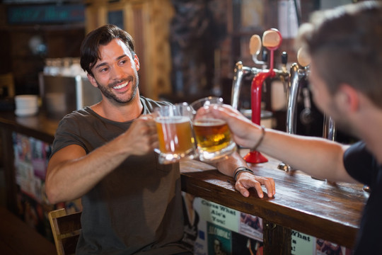 微笑的男人和男朋友在酒吧举杯