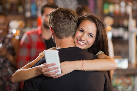 快乐的年轻夫妇在酒吧拥抱