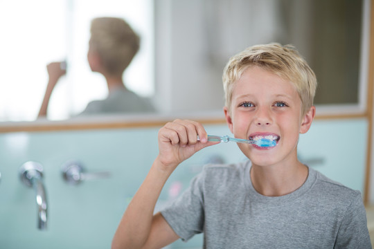 男孩在家里浴室刷牙的照片