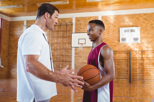 教练站在球场上与篮球运动员交谈