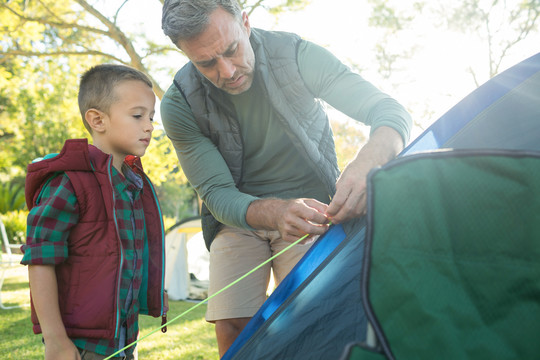 父亲和儿子在晴天在营地搭帐篷