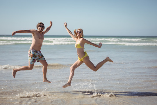 一对快乐的夫妇在海滩上跳来跳去
