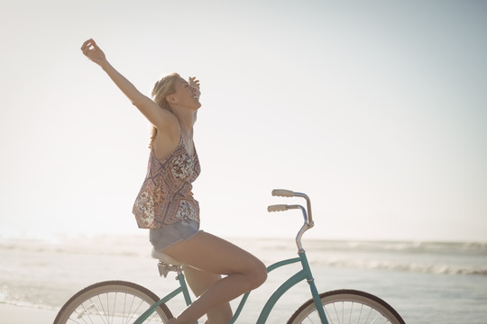 海滩上骑自行车的快乐女人