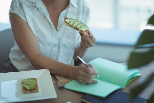 在办公室餐桌上吃饭的女商人