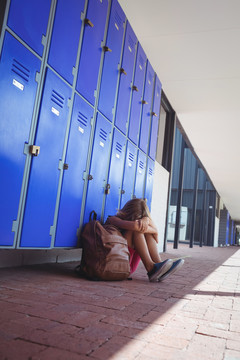 坐在学校走廊储物柜旁的女学生