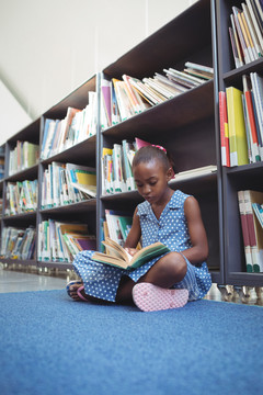 坐在图书馆书架旁看书的女孩