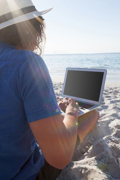在海滩上使用平板电脑的男子