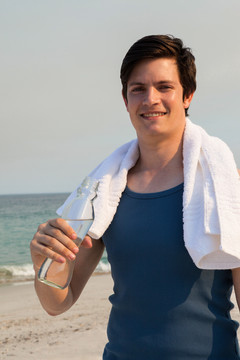 海滩上拿着水瓶的微笑男人