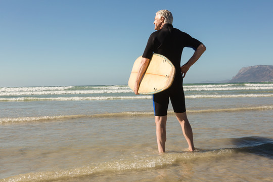 沙滩上拿着冲浪板的老人
