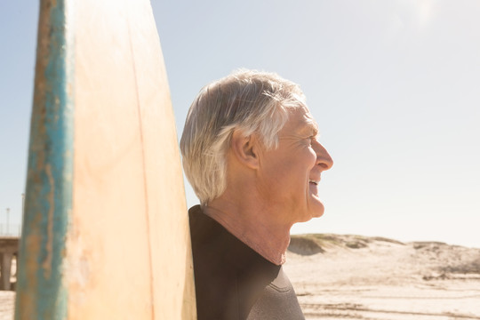 海滩上拿着冲浪板的老人肖像