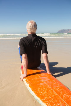 沙滩坐在冲浪板上的老人