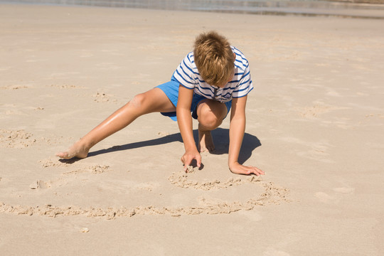 男孩蹲在沙滩上玩沙子