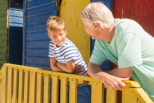 祖父和孙子靠在沙滩小屋的栏杆上