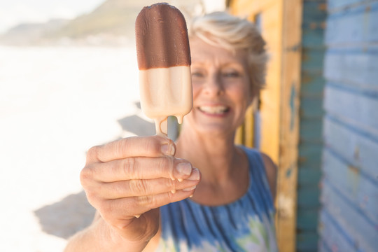 站在海滩小屋边吃冰淇淋的老妇人