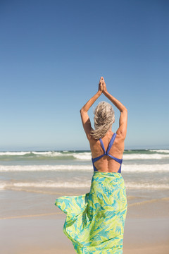 站在海边练瑜伽的女性后视图