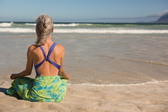 坐在沙滩上靠海沉思的女人