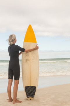 站在沙滩上拿冲浪板的女人
