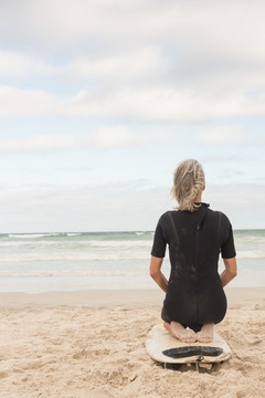 女子跪在沙滩的冲浪板上