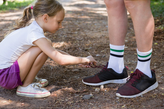 女孩在森林里系着她祖父的鞋带