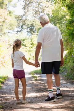 爷爷和孙女在森林里一起散步