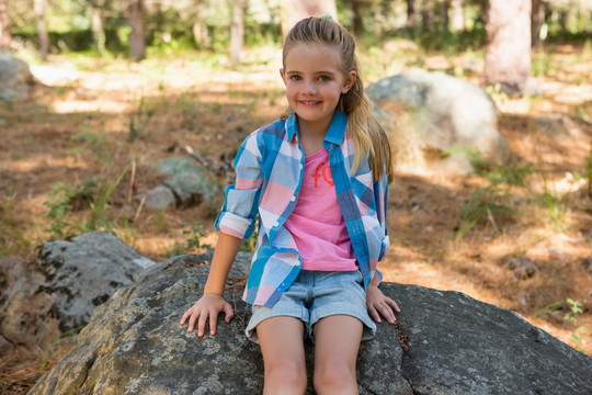 森林中坐在岩石上的女孩